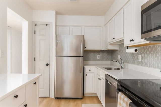 kitchen featuring white cabinets, stainless steel appliances, light countertops, and a sink