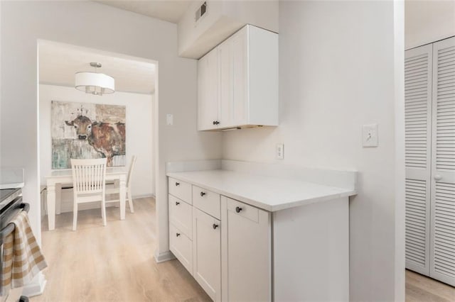 kitchen featuring white cabinetry, visible vents, and light wood finished floors