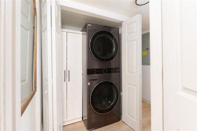 washroom with light wood-type flooring, laundry area, and stacked washer / dryer