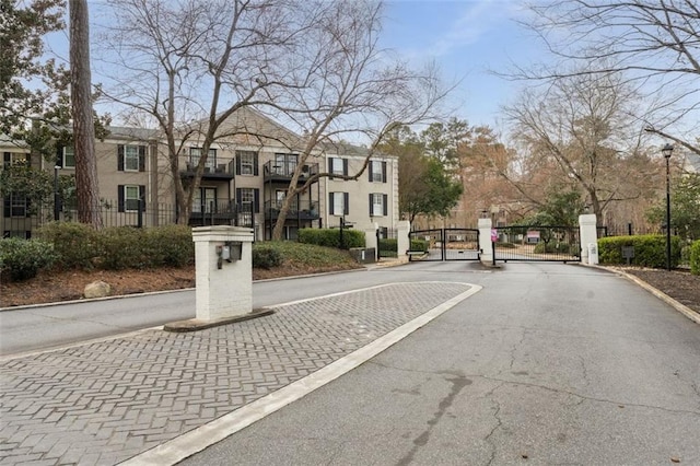 view of road with a gated entry, curbs, street lighting, and a gate