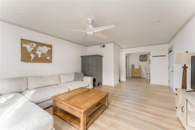 living room with a ceiling fan, visible vents, and light wood finished floors