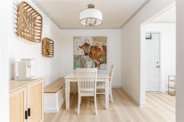 dining room featuring baseboards, light wood-type flooring, and ornamental molding