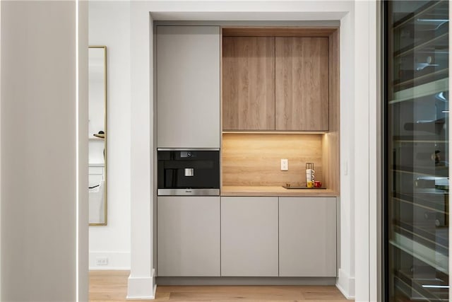 bar featuring wine cooler and light wood-type flooring