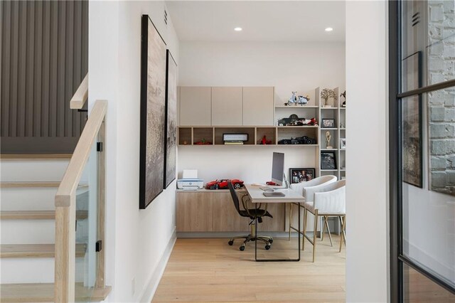 office space with built in desk and light hardwood / wood-style floors