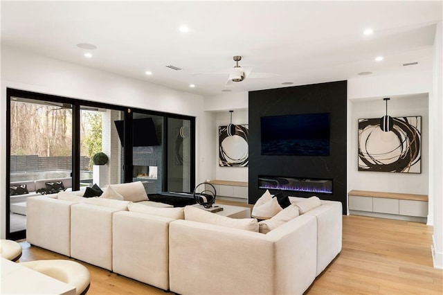 living room with light hardwood / wood-style flooring, a fireplace, and ceiling fan