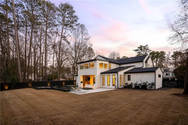 back house at dusk with a yard and a patio