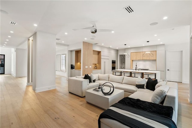 living room featuring ceiling fan and light hardwood / wood-style floors