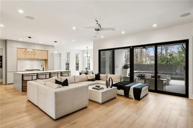 living room with ceiling fan, sink, and light hardwood / wood-style floors