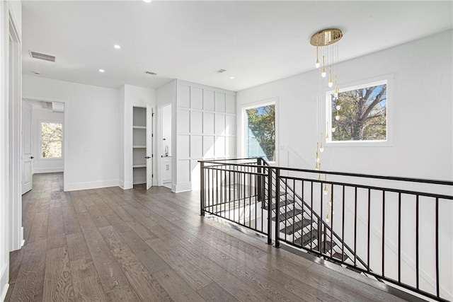 corridor with dark hardwood / wood-style floors and plenty of natural light