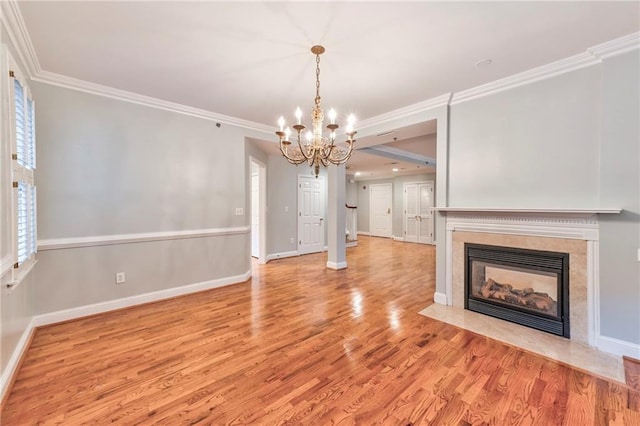 unfurnished living room featuring crown molding, a notable chandelier, a fireplace, and light wood-type flooring