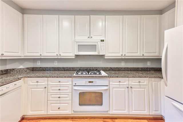 kitchen featuring dark stone countertops, white appliances, white cabinets, and light wood-type flooring