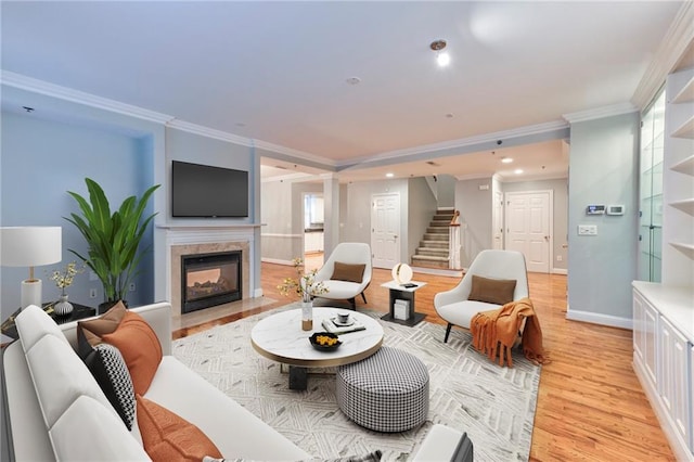 living room with a healthy amount of sunlight, a multi sided fireplace, ornamental molding, and light hardwood / wood-style floors