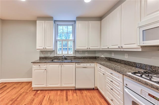 kitchen with white cabinetry, sink, white appliances, and dark stone countertops