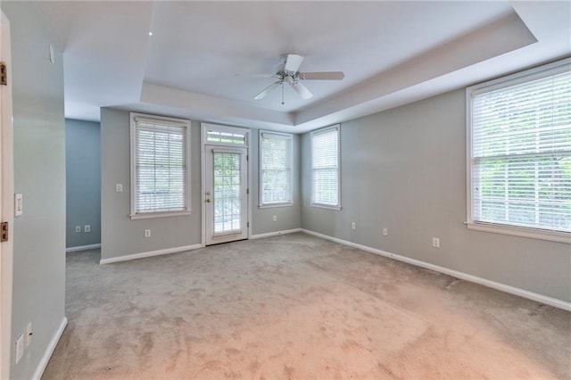 carpeted empty room with a raised ceiling and ceiling fan