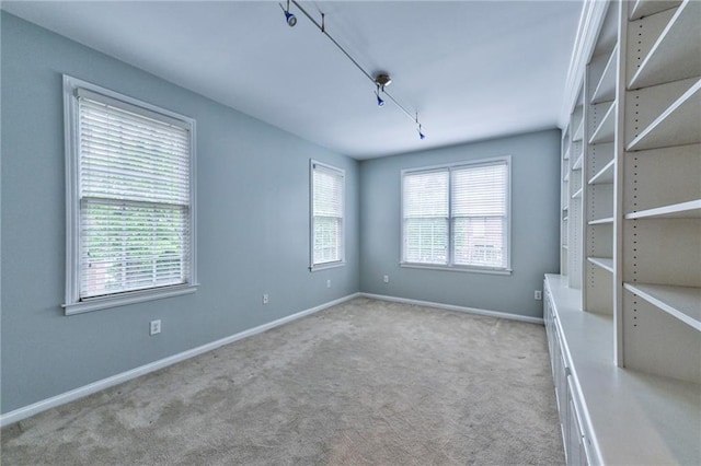 carpeted spare room featuring rail lighting