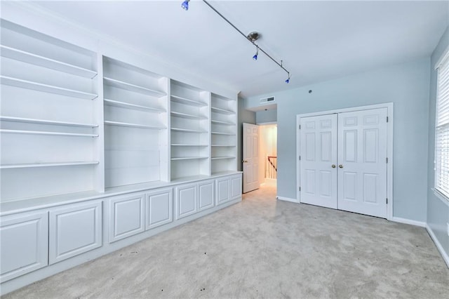 unfurnished bedroom with multiple windows, rail lighting, and light carpet