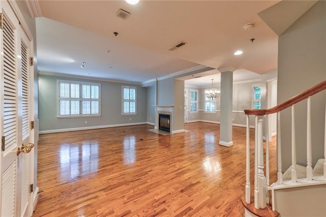 living room with ornamental molding, a high end fireplace, a chandelier, and light hardwood / wood-style floors