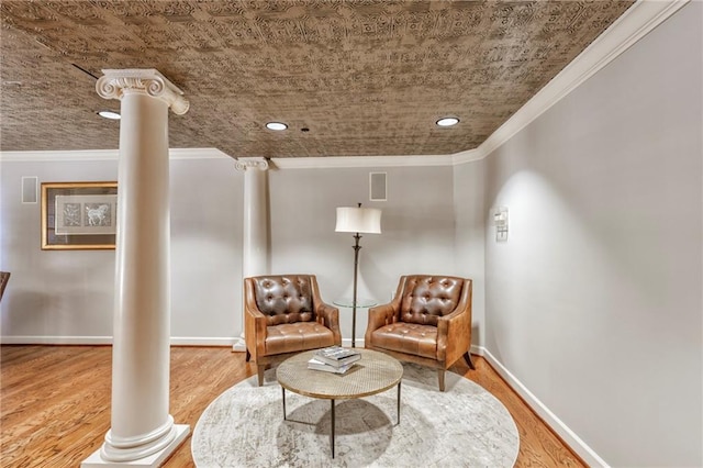 sitting room featuring crown molding, hardwood / wood-style floors, and ornate columns