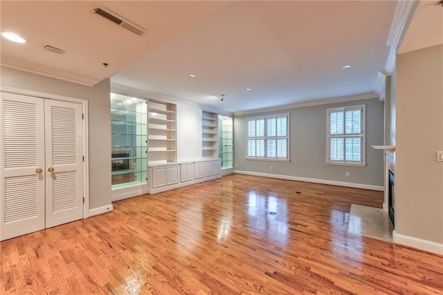 unfurnished living room featuring built in features, light hardwood / wood-style flooring, and ornamental molding