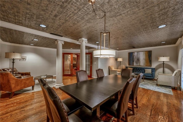 dining room with decorative columns, wood-type flooring, and crown molding