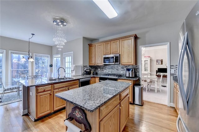 kitchen with stainless steel appliances, a kitchen island, sink, and decorative light fixtures