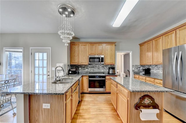 kitchen featuring sink, decorative light fixtures, stainless steel appliances, and a kitchen island