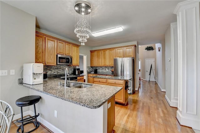 kitchen with sink, stone countertops, decorative light fixtures, appliances with stainless steel finishes, and kitchen peninsula