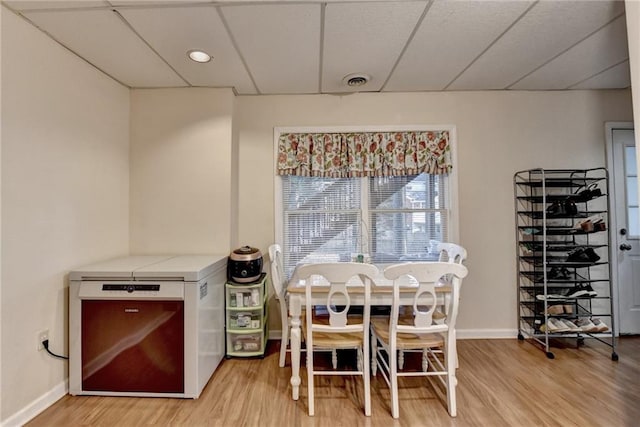 dining space featuring a drop ceiling and wood-type flooring