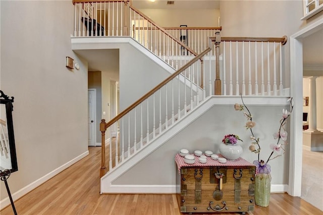 stairs with hardwood / wood-style flooring, ornate columns, and a high ceiling