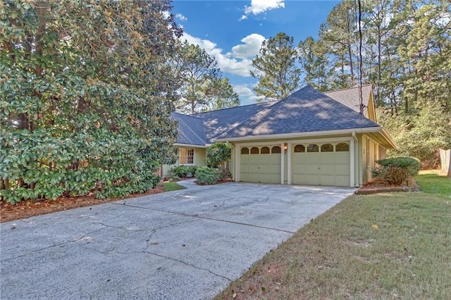 view of front of home featuring stucco siding, a shingled roof, a front yard, a garage, and driveway