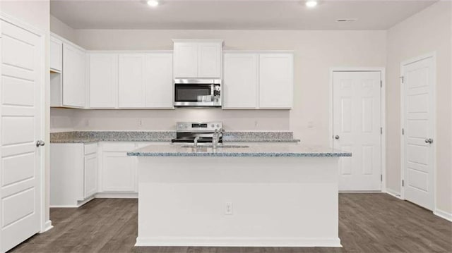 364 Sound Cir, Stockbridge, GA 30281 - kitchen with stainless steel appliances, a center island with sink, dark wood finished floors, light stone counters, and white cabinets