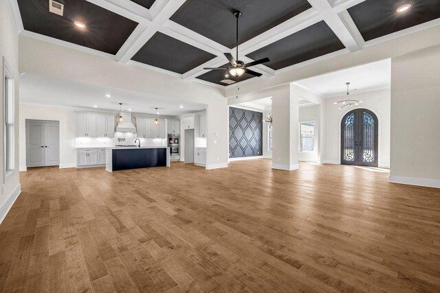 125 Drummond Pl, Covington, GA 30014 - unfurnished living room with coffered ceiling, baseboards, a ceiling fan, light wood-style floors, and a sink