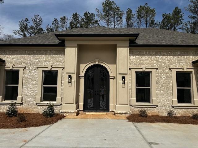 property entrance with brick siding and roof with shingles