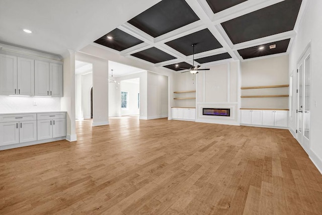 125 Drummond Pl, Covington, GA 30014 - unfurnished living room featuring ceiling fan, a glass covered fireplace, coffered ceiling, light wood finished floors, and beam ceiling