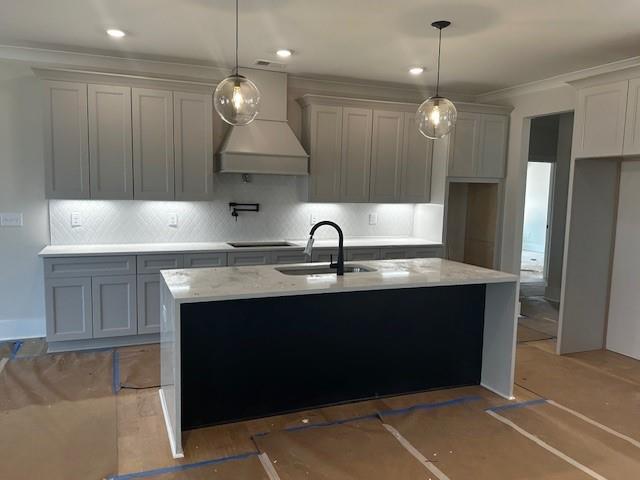 kitchen with tasteful backsplash, ornamental molding, decorative light fixtures, custom exhaust hood, and a sink