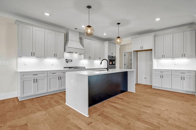 125 Drummond Pl, Covington, GA 30014 - kitchen with custom range hood, stainless steel gas stovetop, a sink, backsplash, and light countertops