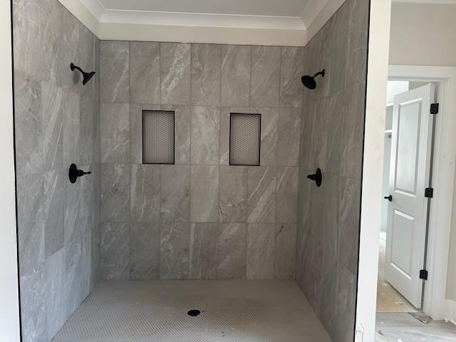 full bath with crown molding and tiled shower