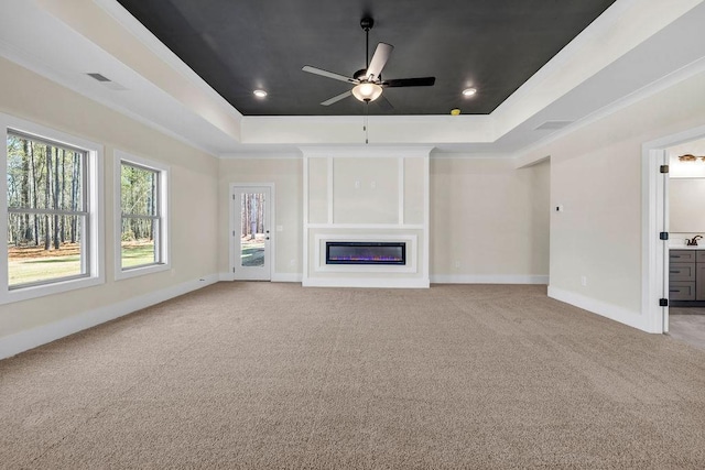 125 Drummond Pl, Covington, GA 30014 - unfurnished living room featuring a raised ceiling, a ceiling fan, light carpet, baseboards, and a glass covered fireplace