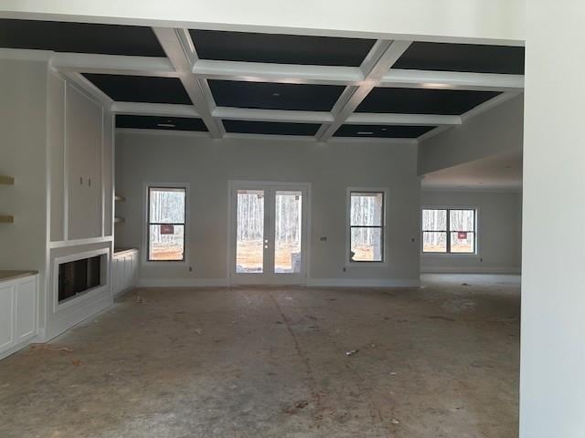 unfurnished living room featuring baseboards, coffered ceiling, beam ceiling, and french doors