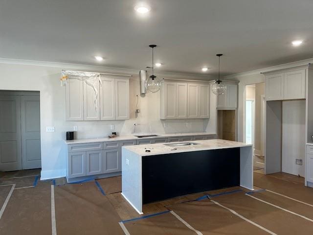 kitchen with recessed lighting, light countertops, ornamental molding, a kitchen island with sink, and stovetop