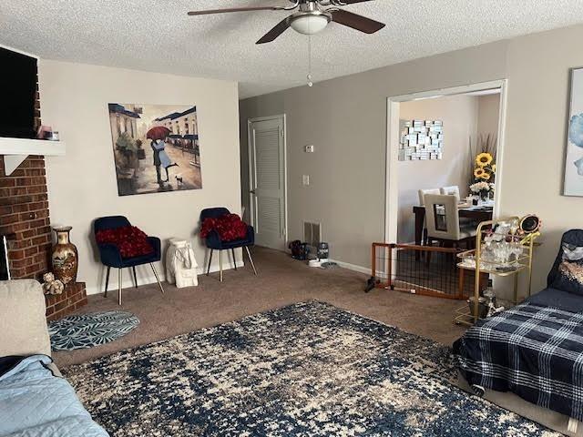 231 Forest Pl, Lawrenceville, GA 30046 - living room with carpet, a ceiling fan, a fireplace, and a textured ceiling
