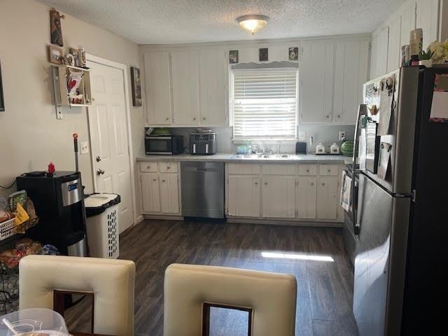 231 Forest Pl, Lawrenceville, GA 30046 - kitchen featuring stainless steel appliances, dark wood-style floors, light countertops, a textured ceiling, and white cabinetry