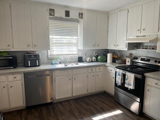 231 Forest Pl, Lawrenceville, GA 30046 - kitchen with appliances with stainless steel finishes, under cabinet range hood, light countertops, dark wood-style flooring, and a textured ceiling