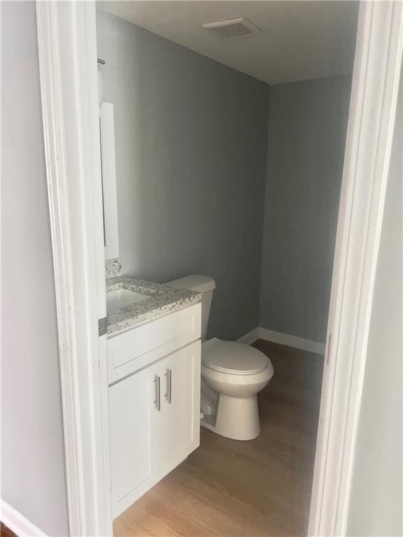 bathroom featuring vanity, wood-type flooring, and toilet