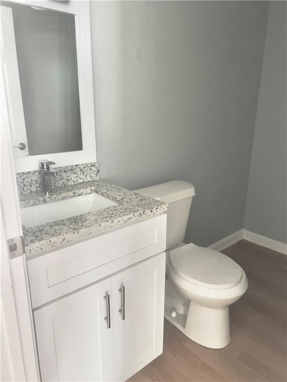 bathroom with vanity, toilet, and hardwood / wood-style floors