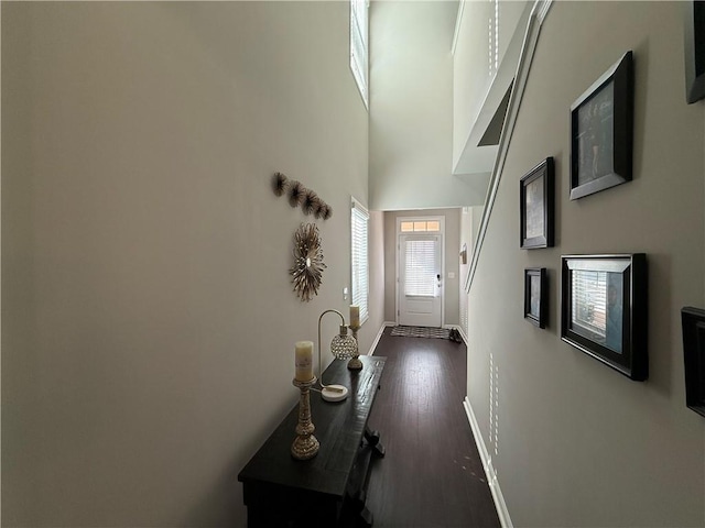 doorway to outside with dark wood-type flooring and a towering ceiling