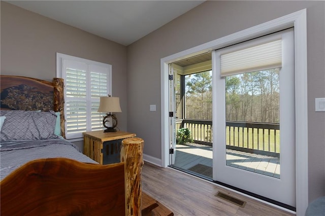 bedroom with access to exterior, wood finished floors, visible vents, and baseboards