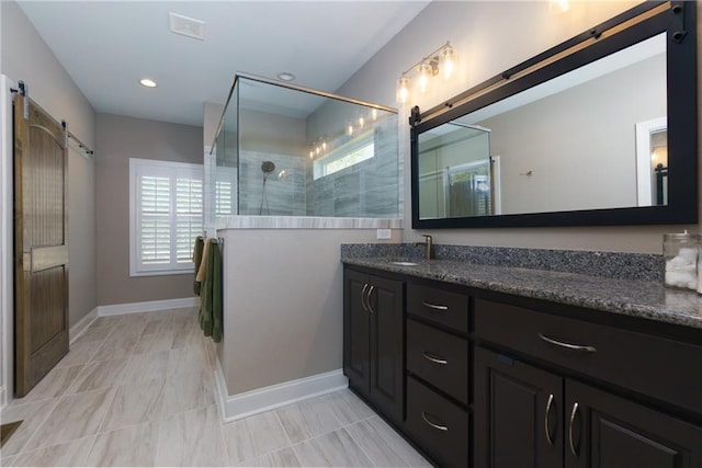 bathroom featuring vanity, a healthy amount of sunlight, baseboards, and walk in shower