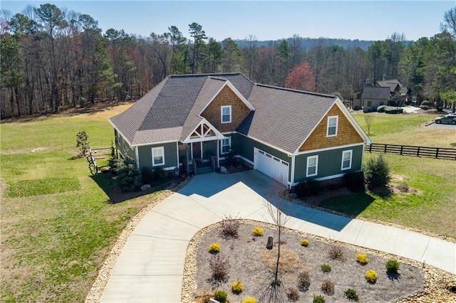 view of front of home with a front yard, fence, and a view of trees