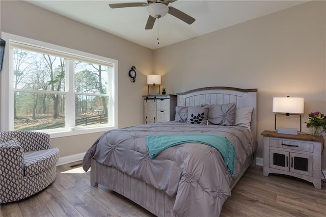 bedroom featuring ceiling fan, baseboards, and wood finished floors